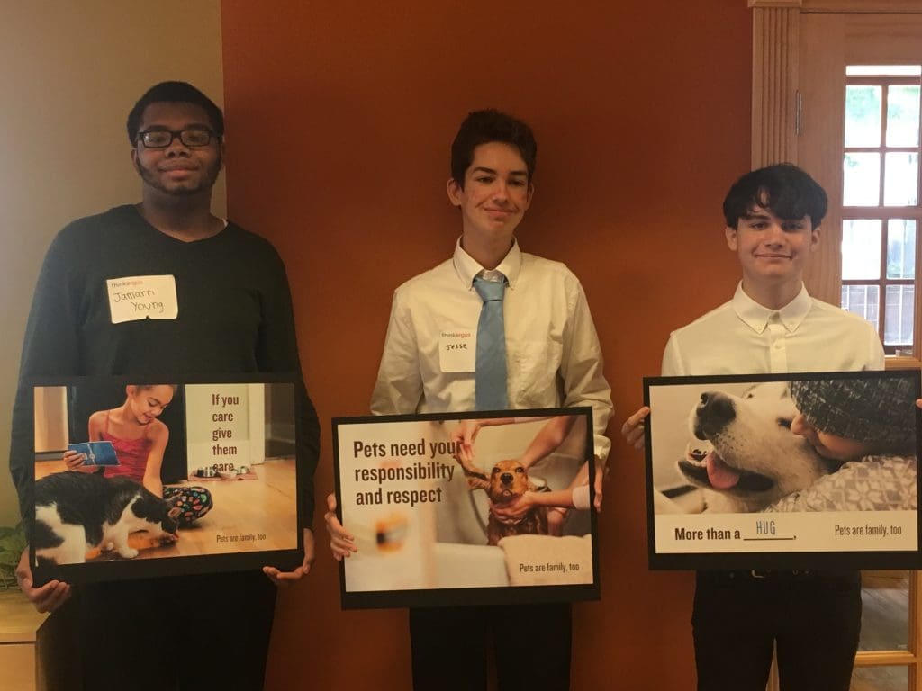 Teen summer interns pose at ThinkArgus with posters they made promoting animal rights 