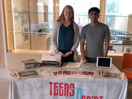 Staff Annie and Elvis standing behind table with Teens in Print materials