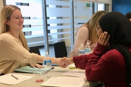 adult professional smiling and shaking hands with a student, preparing for a mock interview