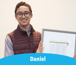 Daniel Smiling student holding framed article