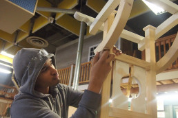 student working on a wooden arch in school