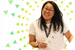 Graphic: photo of a smiling teacher with green and yellow triangles in a sunburst pattern