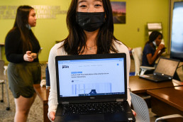 photo of smiling, masked student holding a laptop open to their publication on teensinprint.com