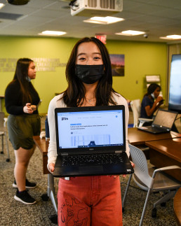 photo of smiling, masked student holding a laptop open to their publication on teensinprint.com