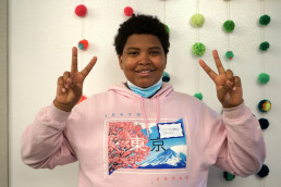 student smiles at the camera holding up two peace signs