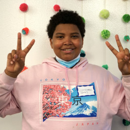 student smiles at the camera holding up two peace signs