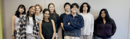 A group of teens facing forward and smiling. A banner above them reads 
