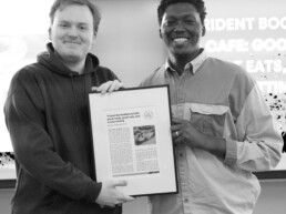 Mohamed and Graham hold a framed article